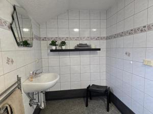 a white tiled bathroom with a sink and a mirror at Apartment - Tor zur Rhön in Vachat