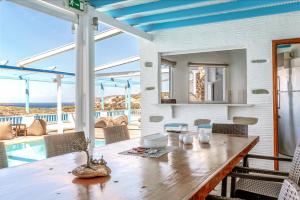 a dining room with a table and a pool at Blue Waves View Andros in Andros