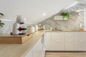 a kitchen with white cabinets and a marble wall at Sky and Sea Haven in Santa Cruz