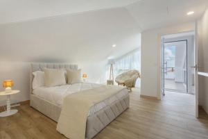 a white bedroom with a large bed and a balcony at Sky and Sea Haven in Santa Cruz