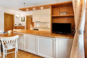 a kitchen with white cabinets and a flat screen tv at Appartamento Le Cigamole in Valfurva