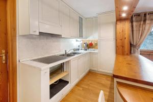 a kitchen with white cabinets and a sink at Appartamento Le Cigamole in Valfurva +15 photos