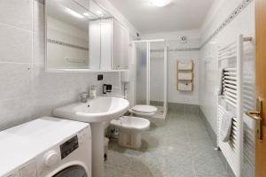 a white bathroom with a sink and a toilet at Appartamento Le Cigamole in Valfurva