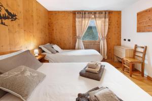 a bedroom with two beds and a chair and a window at Appartamento Le Cigamole in Valfurva