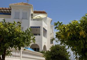 a white house with a white fence and trees at Luxury Sea view Apartment in Nerja