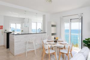 a white kitchen and dining room with a table and chairs at Luxury Sea view Apartment in Nerja
