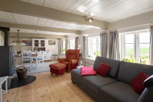 a living room with a gray couch and a kitchen at Ferienwohnungen Appelhus in Pellworm