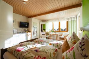 two beds in a room with a kitchen and a living room at Pension Haus Rose in Oberharmersbach