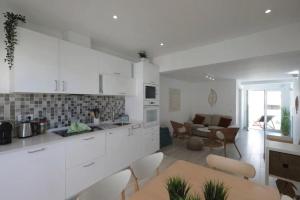 a kitchen with white cabinets and a table and chairs at Bougainvillea House in Tavira