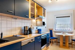 a kitchen with blue cabinets and a table with chairs at Ferienwohnung Sigrun in Niedenstein
