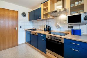a kitchen with blue cabinets and a sink at Ferienwohnung Sigrun in Niedenstein +15 photos