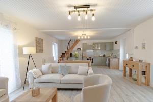 a living room with a white couch and a kitchen at Gite du cerisier in Lanouaille