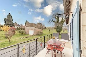 a patio with a table and chairs on a balcony at Gite du cerisier in Lanouaille