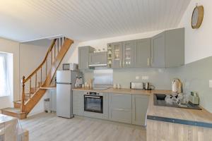 a kitchen with white appliances and a staircase at Gite du cerisier in Lanouaille +21 photos