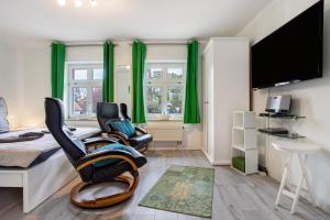 a bedroom with two chairs and a bed with green curtains at Bäckerhus - Ferienwohnung 5 in Wiek auf Rügen