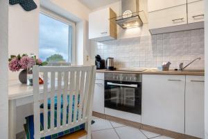 a kitchen with white cabinets and a stove top oven at Bäckerhus - Ferienwohnung 5 in Wiek auf Rügen +13 photos