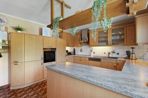 a kitchen with wooden cabinets and a marble counter top at Ferienwohnung am Hügel in Schmallenberg