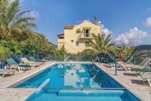a pool with chairs and a house in the background at Veroni's studio 1 in Vathi