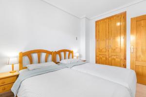 a bedroom with a white bed and a wooden cabinet at Viñamar 7 in La Mata