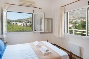 a white bedroom with two towels on a bed with windows at Stunning Views Kantouni Beach in Kalymnos