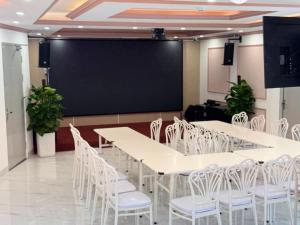 a conference room with white tables and chairs and a large screen at Khách sạn Lâm Hà - Laha Hotel in Riong Serignac