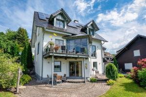 a white house with a balcony and a patio at Am Pön - Ferienwohnungen in Medebach