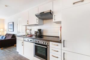 a kitchen with white cabinets and a stove top oven at Solarferienhaus Wolkenlos in Breklum