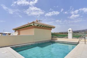 a swimming pool with a house with a roof at Beachfront apartment Torrox Costa in Torrox