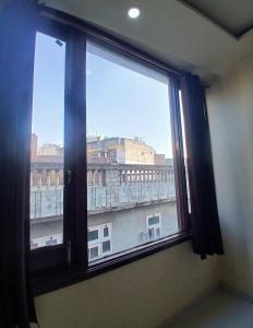 a window in a room with a view of a city at Agam Homestay - Few Steps From golden temple in Amritsar