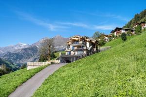 a house on the side of a hill with a road at Sunnseitn Lodge Apartment Alps in Moso
