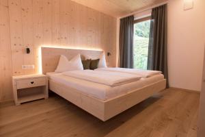 a bedroom with a large white bed with a window at Greiterhof in Lana