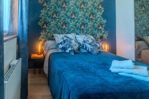 a bedroom with a blue bed with a floral wall at Le Luna in Vindelle