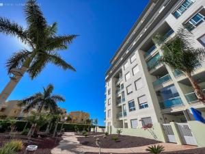 a tall building with palm trees in front of it at Apartamento Isla Feliz in San Miguel de Abona