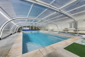 an indoor swimming pool with a metal ceiling at Maison d'Elise in Kerlouan