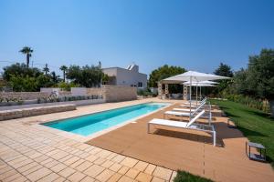 a swimming pool with lounge chairs and an umbrella and a pool at Villa Capobianco in Polignano a Mare