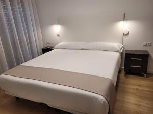 a bedroom with a large white bed and two lights at Apartamento Ejido Centro in El Ejido