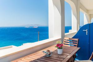 a wooden table with a vase of flowers on a balcony at Ammos Tinos in Istérnia