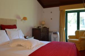a bedroom with a bed and a chair and a window at Quinta Pé Franco in Medrões