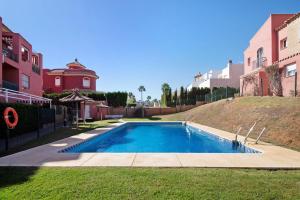 a swimming pool in a yard next to some buildings at Duplex Luminoso Campo de Golf in Islantilla