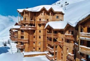 a large wooden building with snow on top of it at Appartement Higginson Val Thorens in Val Thorens