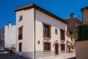 a white building with red windows on a street at Quercus in Navaluenga