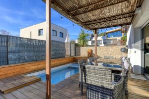 a patio with a swimming pool and a wooden deck at Chambre Villa illiade in Jacou