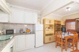 a kitchen with a table and a white refrigerator at Casa Do Sol - Estombar Algarve in Estômbar