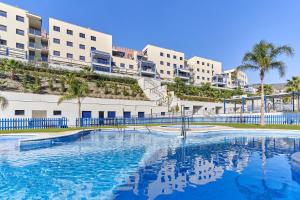a swimming pool in front of some apartment buildings at Apartamento Playa Cabria in Almuñécar
