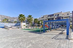 a playground in front of a building with palm trees at Apartamento Playa Cabria in Almuñécar