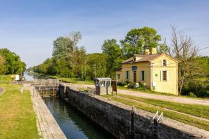 a canal with a building next to a house at Gite de l'Ecluse in Bassanne