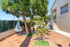 a patio with two palm trees and a hammock at Casa Anglada in Calafell