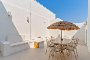 a dining room with a table with chairs and an umbrella at Dimora delle Riserve Naturali in Torre Colimena