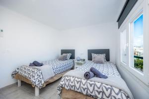 two beds in a room with a window at Can Picafort Sea Breeze in Can Picafort