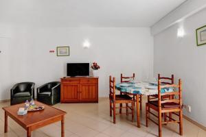 a living room with a table and chairs and a tv at Casa Ferrão in Armação de Pêra
